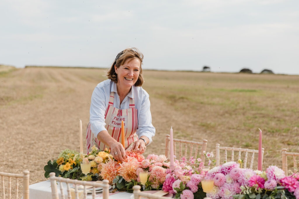 Justine of Farhill Flowers sets up a wedding breakfast table with British cut flowers for a rural festival weddding. Photo: Michelle Hugglestone.