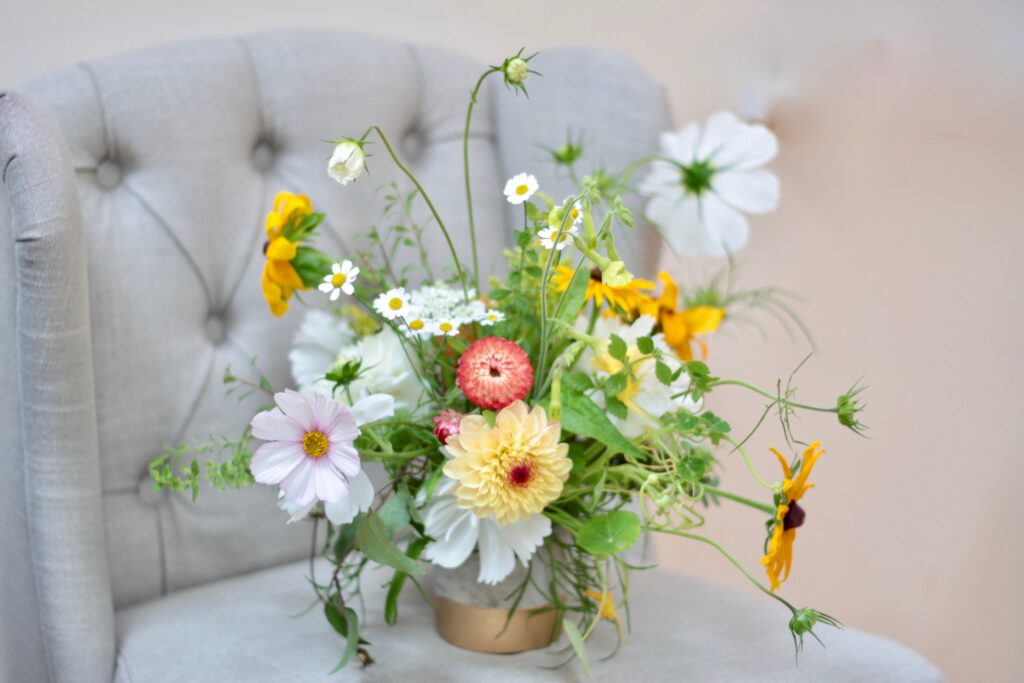 A small wild arrangement with yellow rudbeckia, dahlias and airy pale pink and white cosmos daisies. Tuckshop Flowers