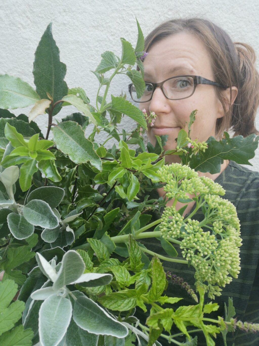 Kate of Greenery Flowers peeps out from behind a huge bunch of chunky sedum, silvery senecio and aromatic bay leaves