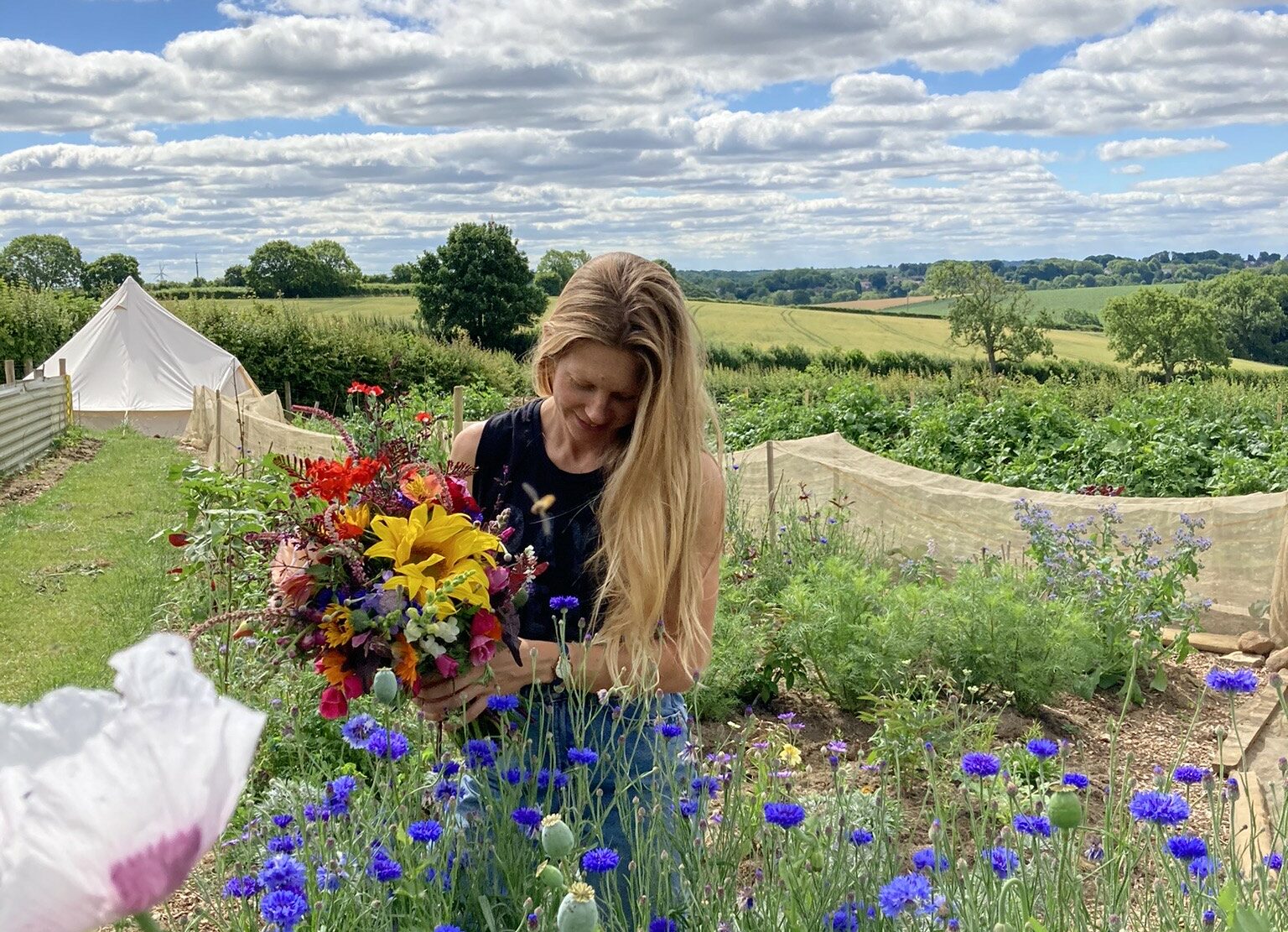 Sammie Hall at work gathering flowers on her plot, against an idyllic rural backdrop