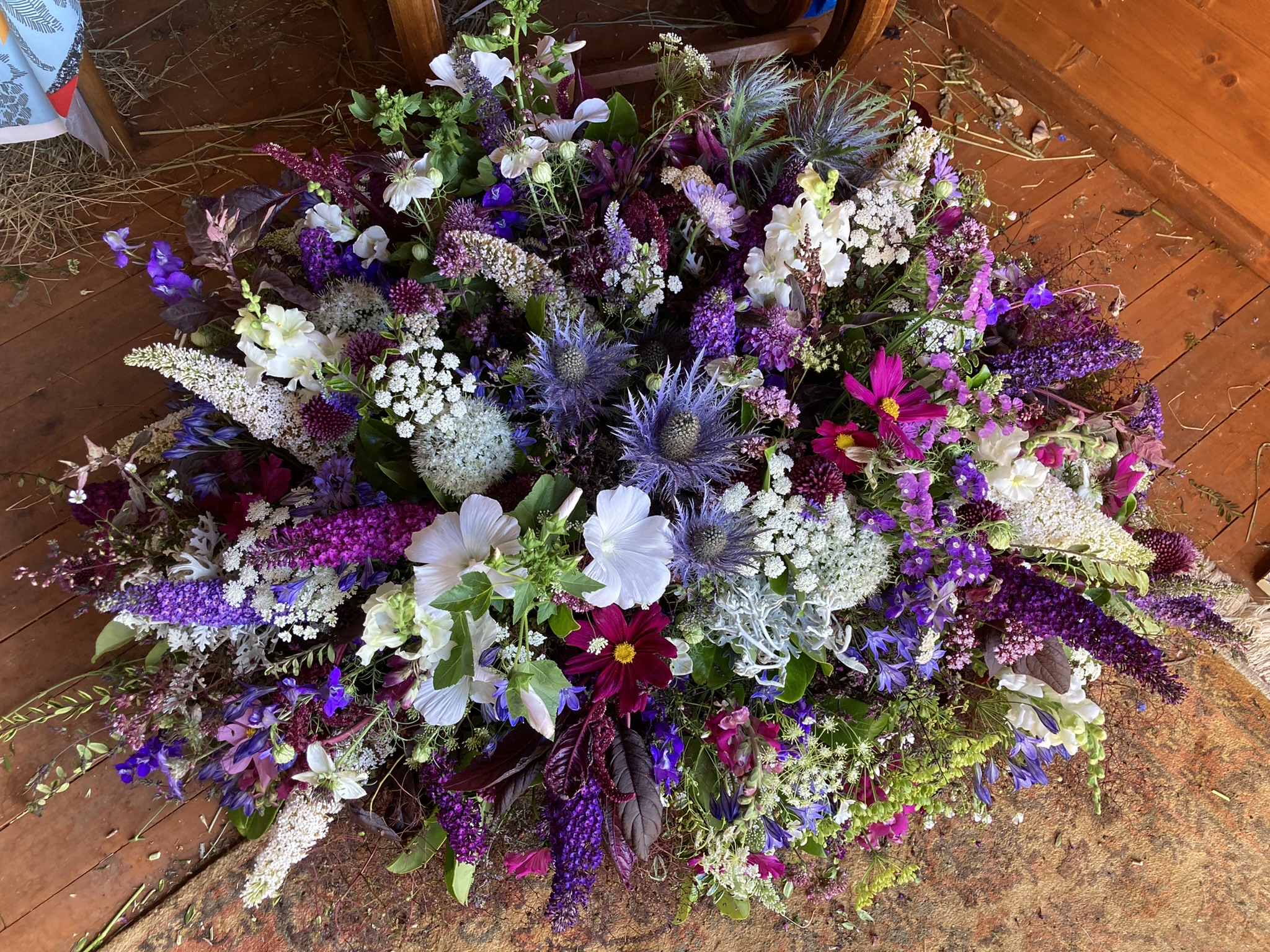 A beautiful example of a seasonal floral funeral tribute by Sammie Halll, including buddleia, cosmos and eryngium