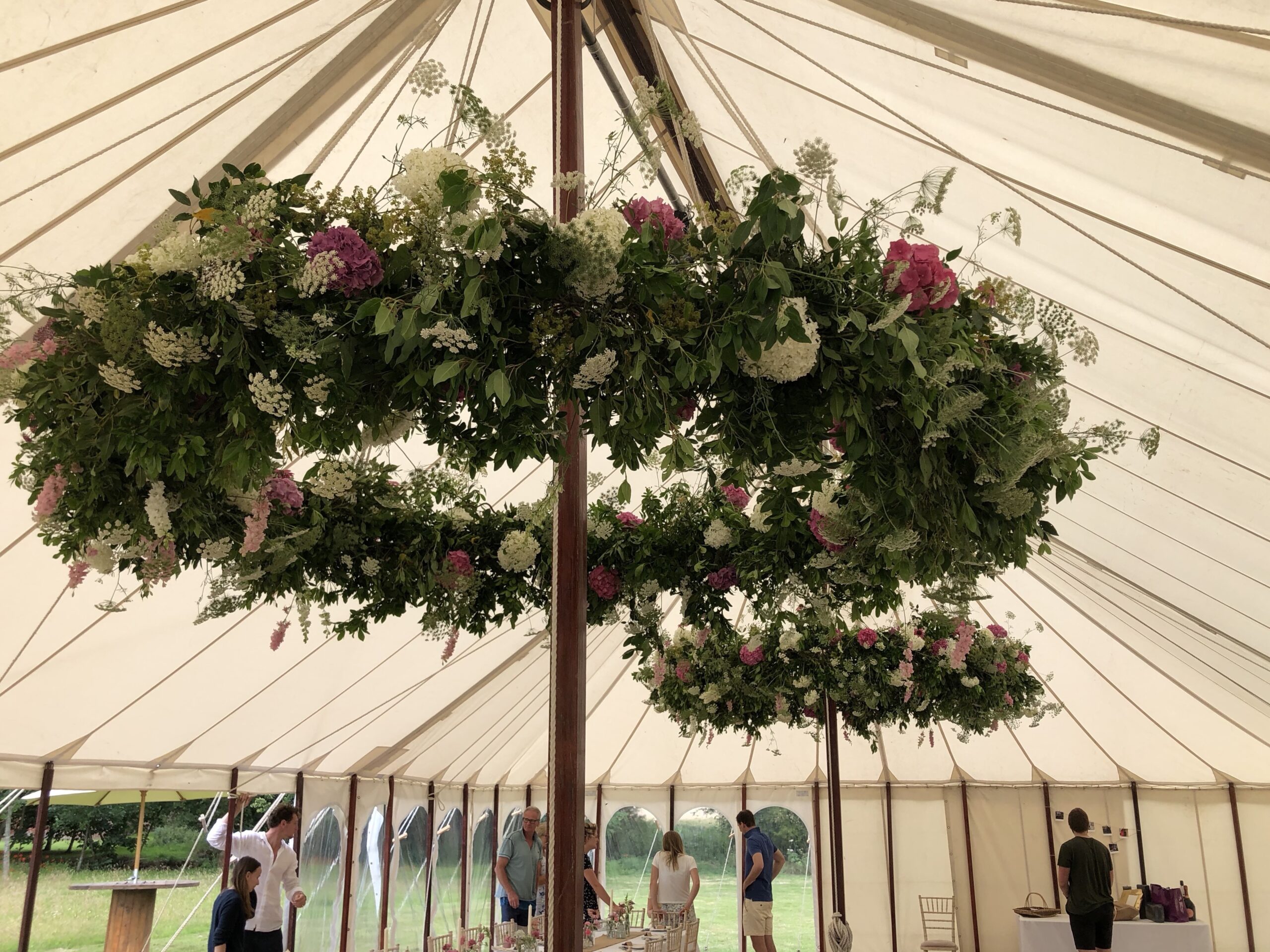 Large suspended floral hoops by Moat Farm Flowers decorate a marquee