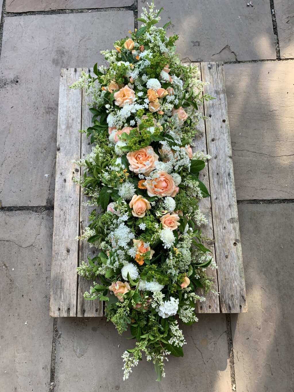 A seasonal casket arrangement of British flowers designed by The Posy Patch