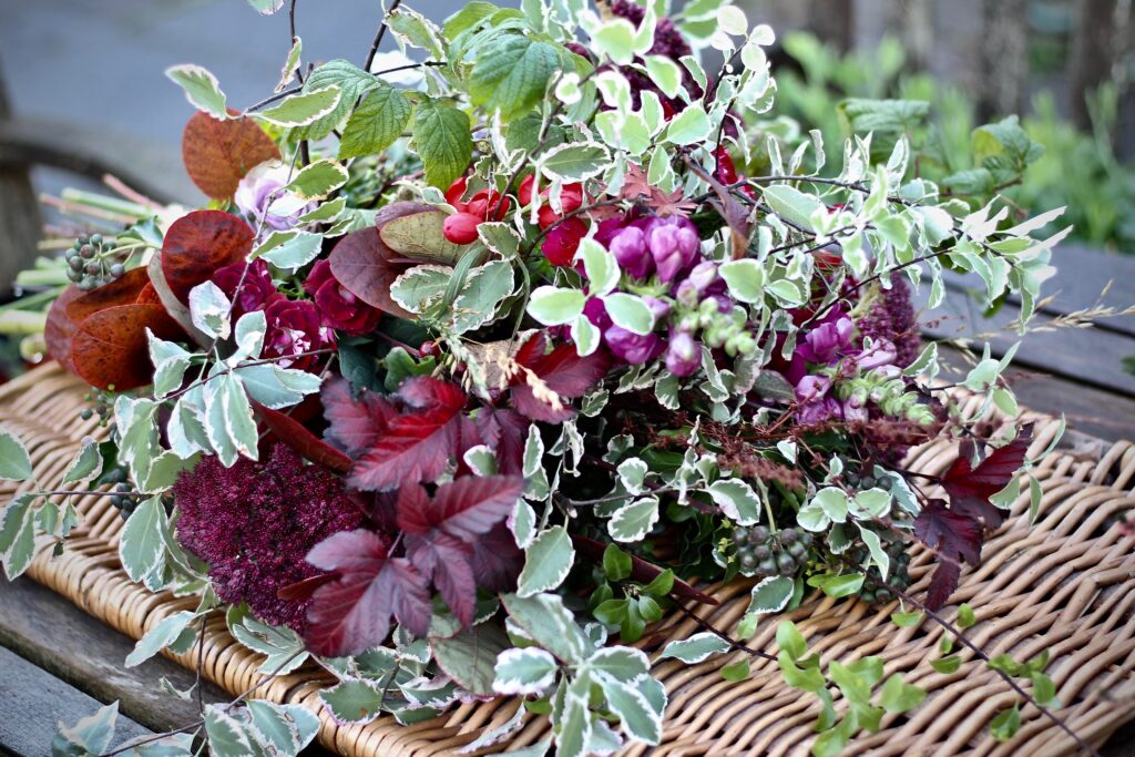 A foliage inspired funeral sheaf with Burgundy physocarpus, variegated pittosporum and ivy is full of texture and colour. Tuckshop Flowers