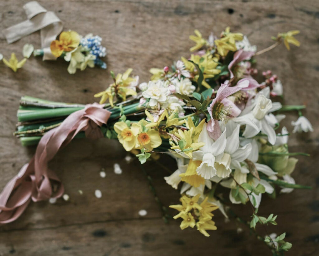 A soft romantic bouquet of yellow and white narcissi with touches of pink from speckled hellebore blooms and silk ribbon.