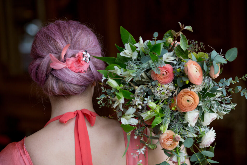 Bridesmaid holding a bouquet with coral ranunculus and alstroemeria by Wildly Beautiful Flowerers.