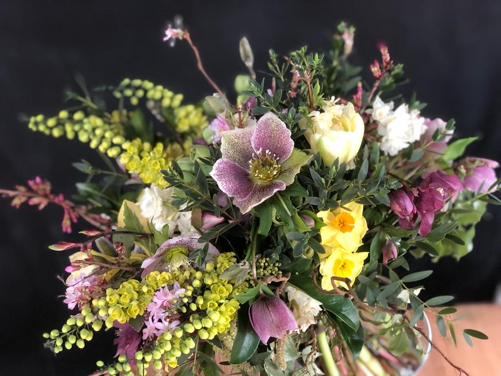 Pink Hellebores and yellow Mahonia flowers in a late winter bouquet.